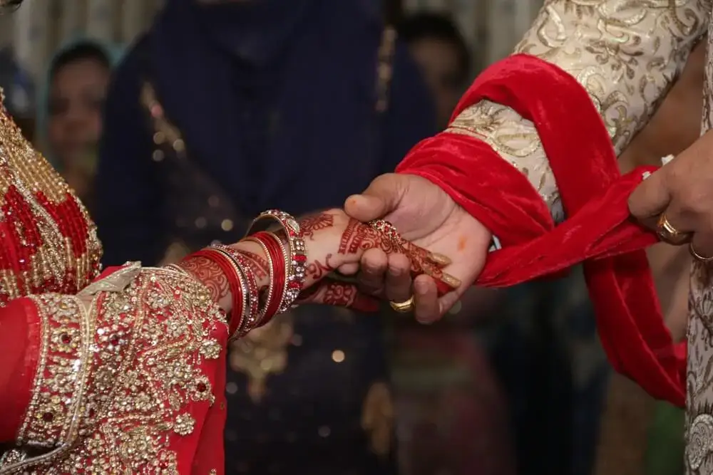 a sikh couple holding hands on their wedding expressing Punjabi Love Shayari - theshayarihub.com